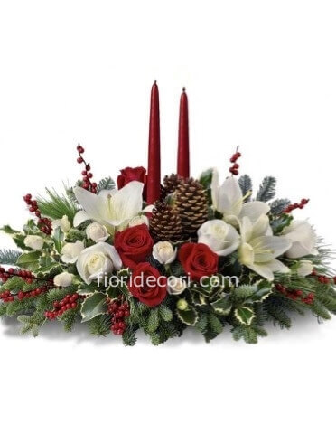 Composizione natalizia con fiori rossi e bianchi, candele e abete con altri decori.